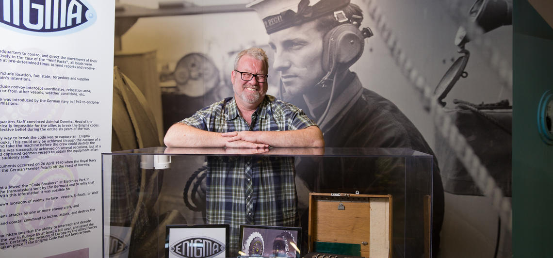 John Ferris stands in front of a display case full of historic artifacts.