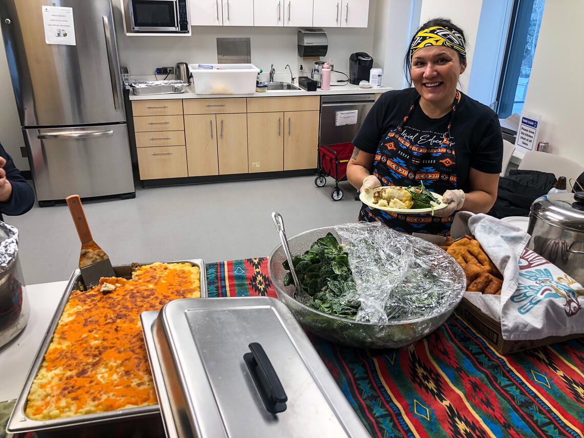 A smiling woman serves food 