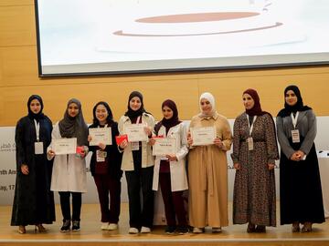 A group of students stand on stage with their awards