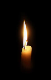A single candle flame burns in a black space