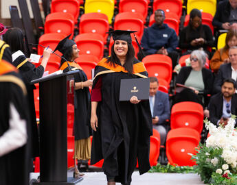 female student walking the stage at spring convocation ceremony 024
